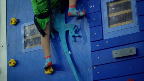 Child is training on the climbing wall with an instructor. Children's rock climbing in a private school.Climbing exercises.School-age girl climbs wall of a climbing wall.Saigon, Vietnam, April 6, 2022