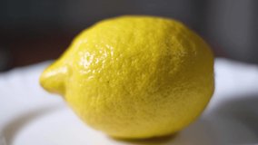 Macro video of a whole ripe yellow lemon, it rotates in a circle.