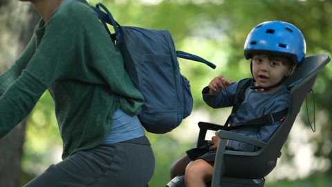Child in bicycle back seat riding together with parent outside wearing helmet