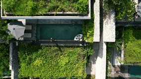 Aerial top down view of a young couple poolside at a luxury tropical villa with a floating breakfast on a sunny summer day in Bali Indonesia - Powered by Shutterstock - Get 15% off with code: PIKWIZARD15