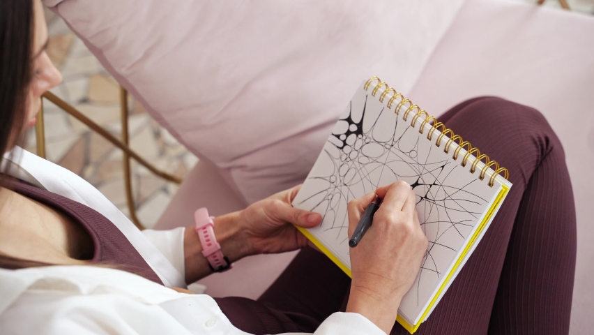 Young woman drawing neurographics indoors. Psychology treatment. Home vacation portrait. Alone in interior. Happy emotion. Smiling female person. Lifestyle action. Posing on chair