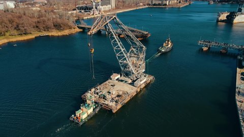 Tugboat pulls floating crane along river to shipyard in Nikolayev Ukraine few days before start of armored invasion. Logistics concept of water cargo transportation