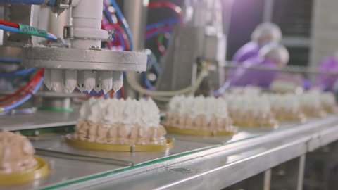 Automated conveyor for creating an ice cream cake. Automated production of ice cream. Ice cream squeezed out of tubes