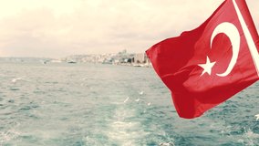 4k Turkish flag on Bosphorus. City view of Istanbul. Seagulls flying. Windy weather.