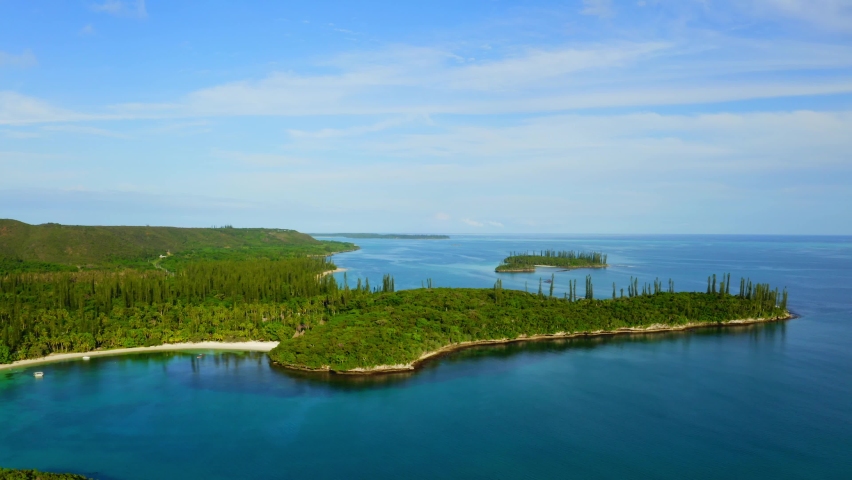 Drone shot moving forward toward a tropical coast with some little islands and beaches during a beautiful day.