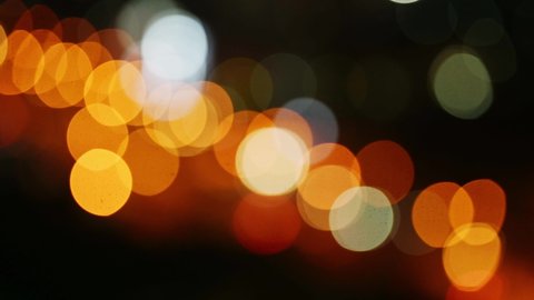 Beautiful glittering bokeh in dark blurry background at night. The round colorful bokeh shine from car lights in traffic on city street. It reflect lonely capital city lifestyle. Abstract concept.