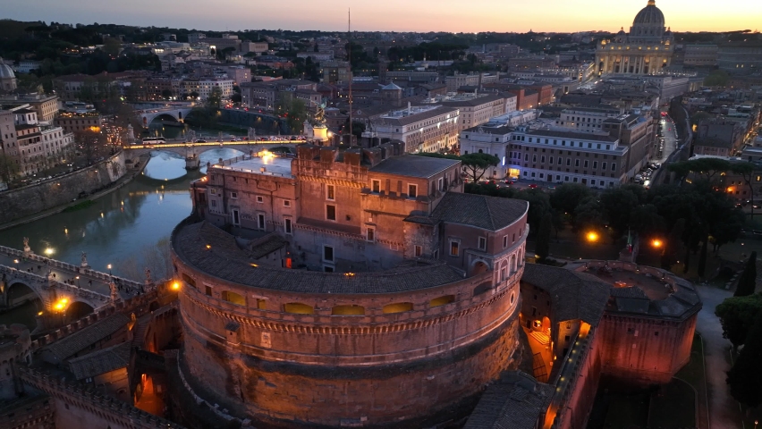 flying above Castel Sant'Angelo and San Pietro in Rome at night. Panoramic aerial view of the Tiber river, its bridges and St. Peter's, Vatican City. Center city of Roma, Italy in the evening.  Royalty-Free Stock Footage #1089475319