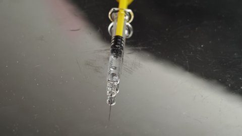 Syringe with vaccine on a bright reflecting background, single dose ready for administration to the patient.