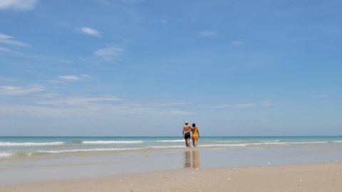 Happy couple in love, playing on the beach at sunny, running and splashing in the waves, travel vacation lifestyle.
