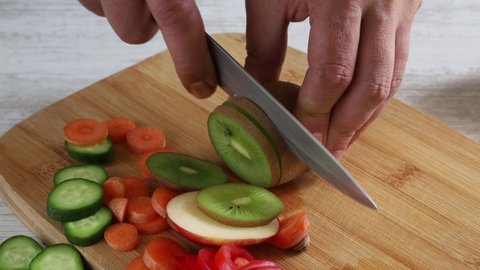 a man cutting kiwi on chopping board
