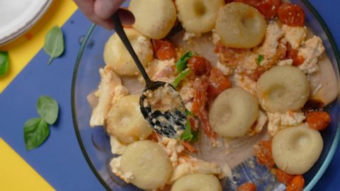 Vertical tabletop video: chef takes cooked potato dumpling with tomatoes and feta cheese by spoon
