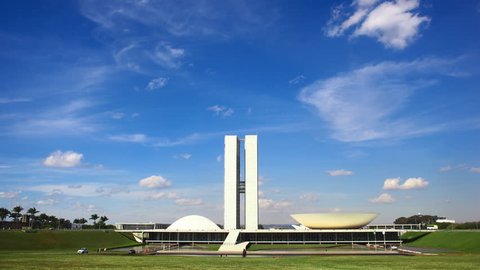 A time-lapse video of the National Congress of Brazil with a blue sky and white clouds.
