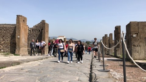 Pompeii, Campania, Italy - APR16, 2022:Tourists explore the ruins of Pompeii, main street of site, Italy.
