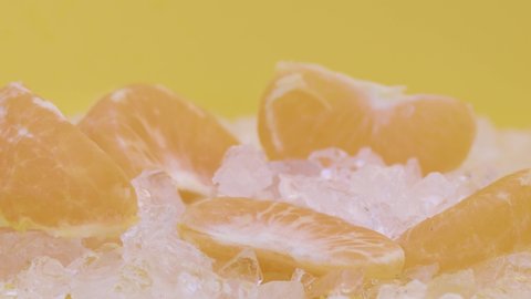 Tangerine whole on the table on a yellow background, water drop falling on the fruit. Slow motion, 8K downscale, filmed on high speed cinema camera. 4K.
