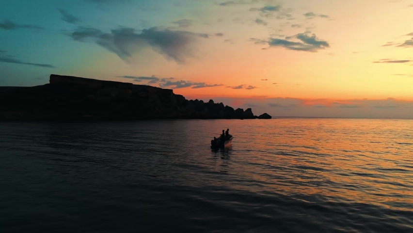 A silhouette of two fishermen enjoying a beautiful sunset in their boat while fishing | Shutterstock HD Video #1089492753