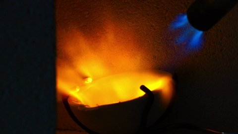 Flames bursting from a crucible used to melt metal for jewelry making. 