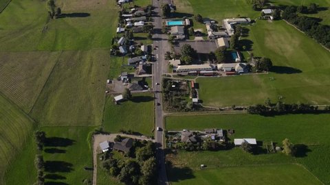 Traffic on main road to Tapawera small town in New Zealand - aerial birds eye view, houses, public and commercial buildings