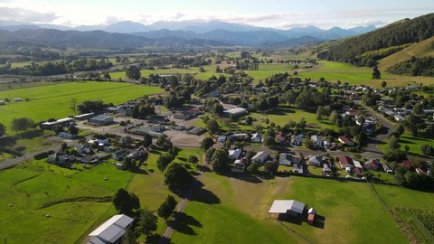 Picturesque small town Tapawera, shop, gas station,public and house buildings in river valley. New Zealand rural - aerial drone rising
