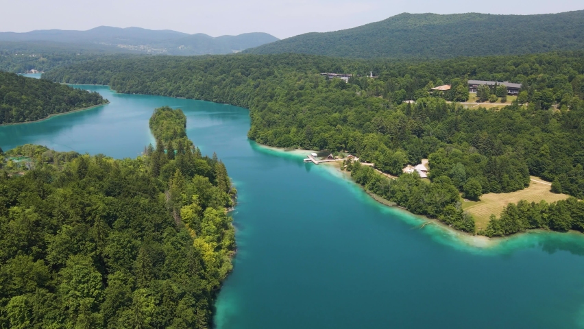 View of the Plitvice Lakes National Park with many green plants and beautiful lakes and a jetty on the shore. Croatian nature