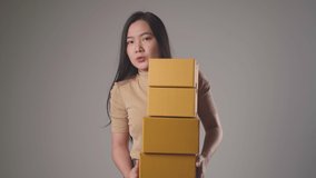 Confident asian woman happy holding stacks boxes dancing smilling and looking at camera isolated over background. 4K video.