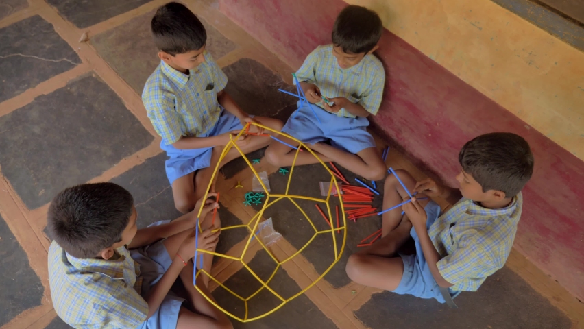Indian village school boys wearing uniforms sit together on the premises busy playing group practical activities or constructive games in a rural area. Concept of education and self learning Royalty-Free Stock Footage #1089501613