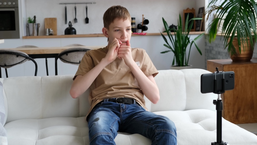 Teenage boy learns to play the folk musical instrument jew's harp online. Distance music education or hobby. Slow motion Royalty-Free Stock Footage #1089504315