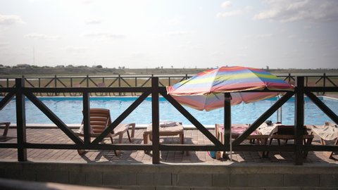 Bright sunny summer weather at the resort, sun bright rays shine on empty sun loungers by the hotel pool