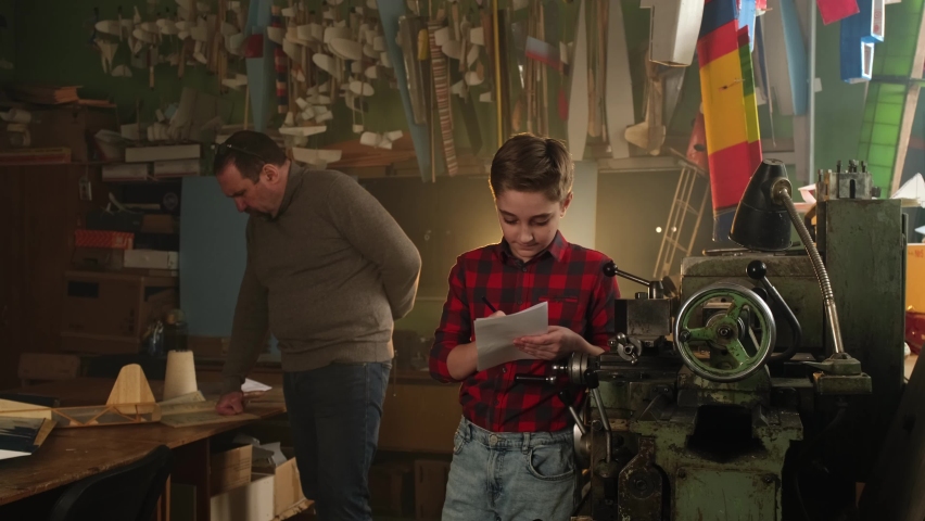 The master teaches the apprentice how to work with a metalworking machine