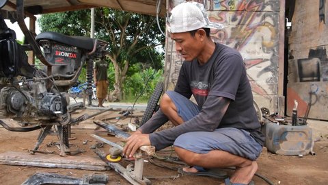 Lampung, Indonesia, April 22 2022: Man grinding and polishing metal professional pipe with sparks in the motorcycle repair shop