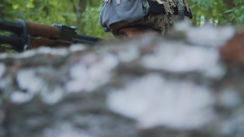 Close up portrait soldier holding machine gun forward to attack enemy in forest. Machine gun barrel look at camera.