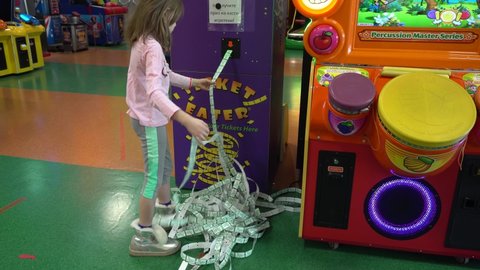 The little girl won at the slot machines. Game center in the mall. The device gives out the won prizes and tickets. Perm, Russia, March 31-2022