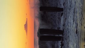 Storm waves crash against old reinforced concrete pillars on the beach against the background of a colorful and red orange sunset, a storm at sea. vertical video - Powered by Shutterstock - Get 15% off with code: PIKWIZARD15