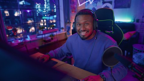 Excited Streamer Talking and Entertaining Followers During Live Broadcast Online. Stylish Black Man Streaming His Life and Personal News from Home Living Room Apartment.