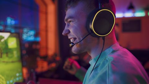 Gaming at Home: Gamer Playing Online Video Game on Computer. Close Up Portrait of Successful Male in Headphones Enjoying Leisure Time, Celebrating Round Win. Cyber Gaming Stylish Retro Neon Room.
