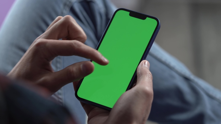 Man Using Smartphone in Vertical Mode with Green Mock-up Screen, Doing Swiping, Scrolling Gestures. Internet Social Networks Browsing News, Financial Reports Royalty-Free Stock Footage #1089511103