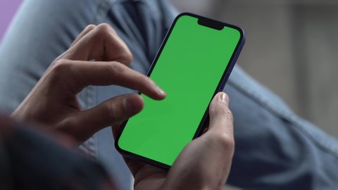 Man Using Smartphone in Vertical Mode with Green Mock-up Screen, Doing Swiping, Scrolling Gestures. Internet Social Networks Browsing News, Financial Reports : vidéo de stock