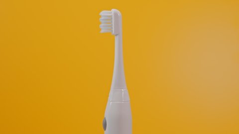 Electric ultrasonic toothbrush on yellow background.