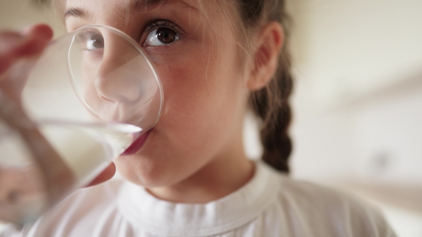 Child girl drinking water from a glass cup. the problem of lack of clean drinking water in the world. little girl in the kitchen lifestyle drinks drinking water from a transparent glass cup | Shutterstock HD Video #1089514151