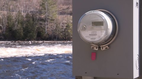 Bracebridge, Ontario, Canada April 2022 Power meter with rushing water of hydro electric dam in background