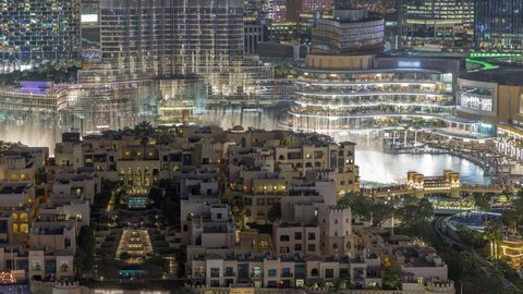 Aerial view to illuminated traditional houses of old town island night timelapse from above. Dubai downtown with fountains area near mall and souk. Evening show