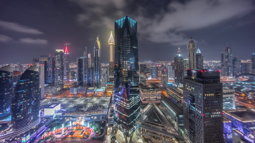 Panorama of futuristic skyscrapers in financial district business center in Dubai on Sheikh Zayed road night timelapse. Aerial view from above with illuminated office towers