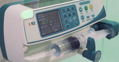 Infusion pump working in hospital background. Dropper monitor, close-up. Syringe infusion pump. Side view intravenous infusion syringe pump. IV infusion. Anesthesia delivery system. Medical equipment