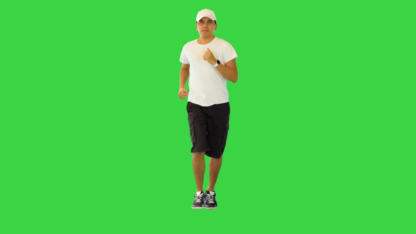Hispanic man jogging check heart beat pulse on smart watch Athletic runner training for competition on a Green Screen, Chroma Key.