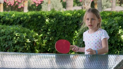 Youth girl play table tennis use small red rackets. Child player hit lightweight ping-pong ball back and forth across hard table divided by tennis net. Happy positive emotion, successful activity
