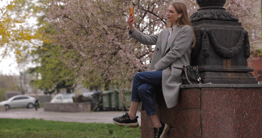 Woman talks with her friend by video chat online in the park