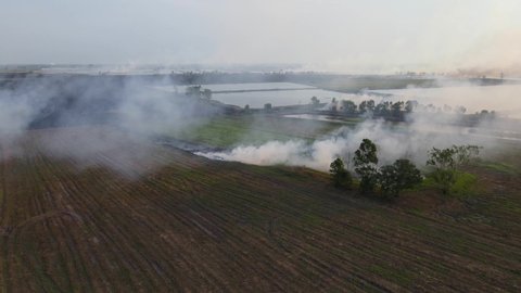 Aerial reversing footage of a farmland burning in Pak Pli, Nakhon Nayok, Thailand.
