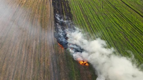 Steady aerial footage revealing a burning and smoking part of a farmland in Pak Pli, Nakhon Nayok, Thailand.