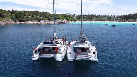 Phuket, Thailand, 19, December, 2020:
Sailing catamarans in the bay of a tropical island, rear view from a drone of sailing boats in a tropical landscape