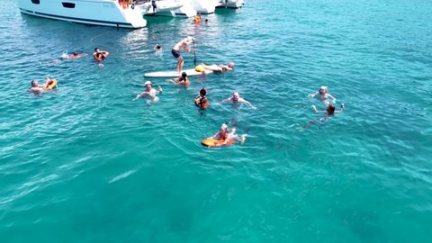 Phuket, Thailand, 19, December, 2020:
A lot of tourists swim in the water near sailing catamarans, a drone view of European tourists relaxing in the tropics during a boat trip