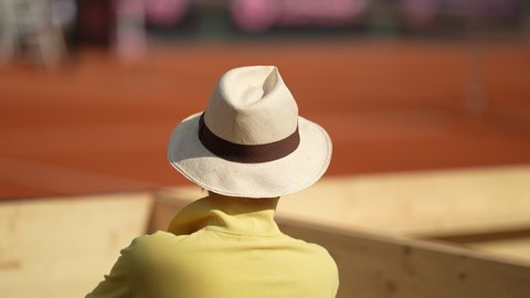 Spectator watching sport match game from stadium seat wearing panama hat